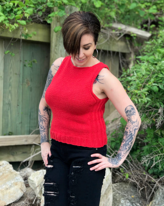 A person wearing a red Avalon tank top with a crew neckline, paired with black denim and standing outdoors.