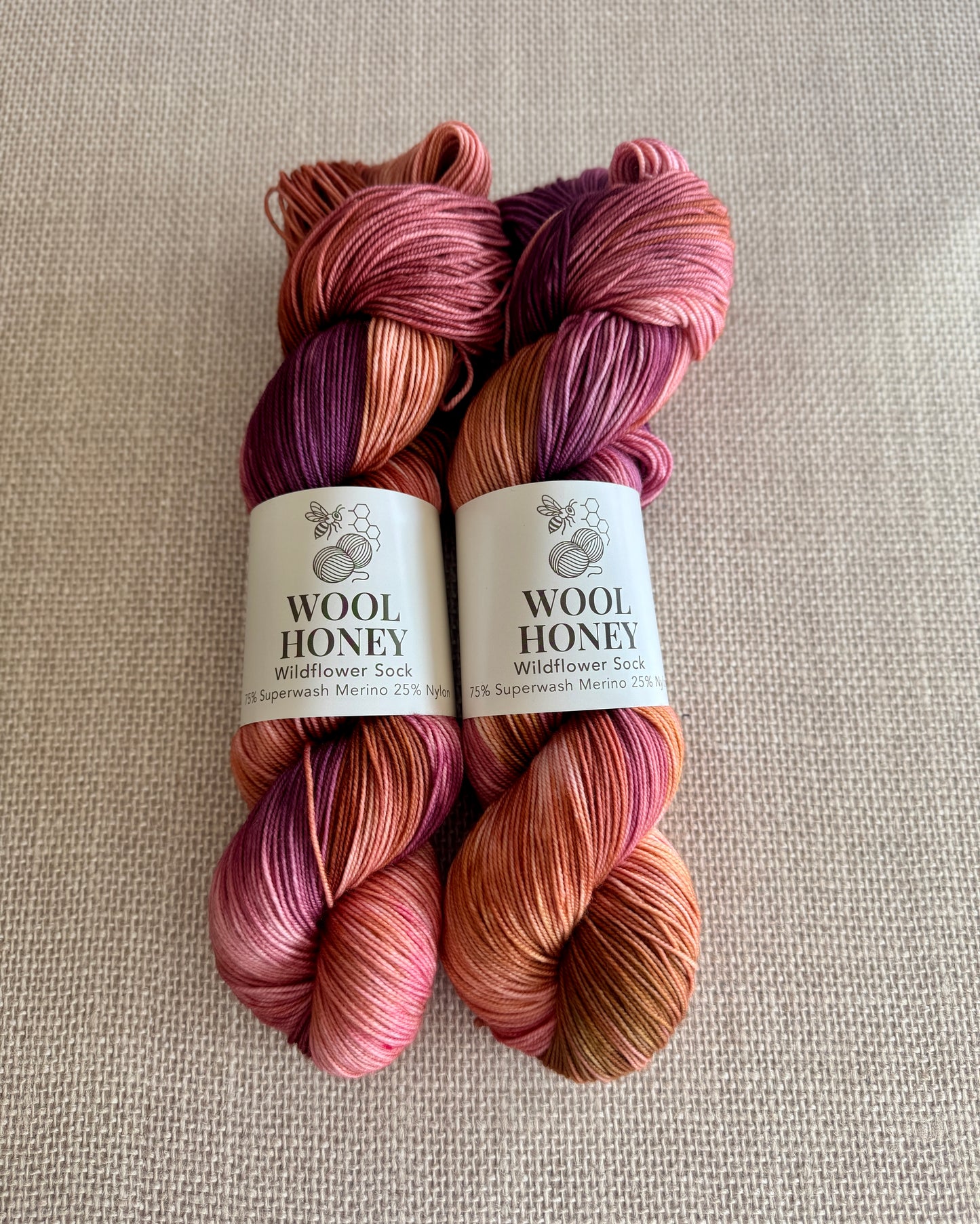 Two skeins of multicolored yarn with 'Wool Honey' labels on a beige background