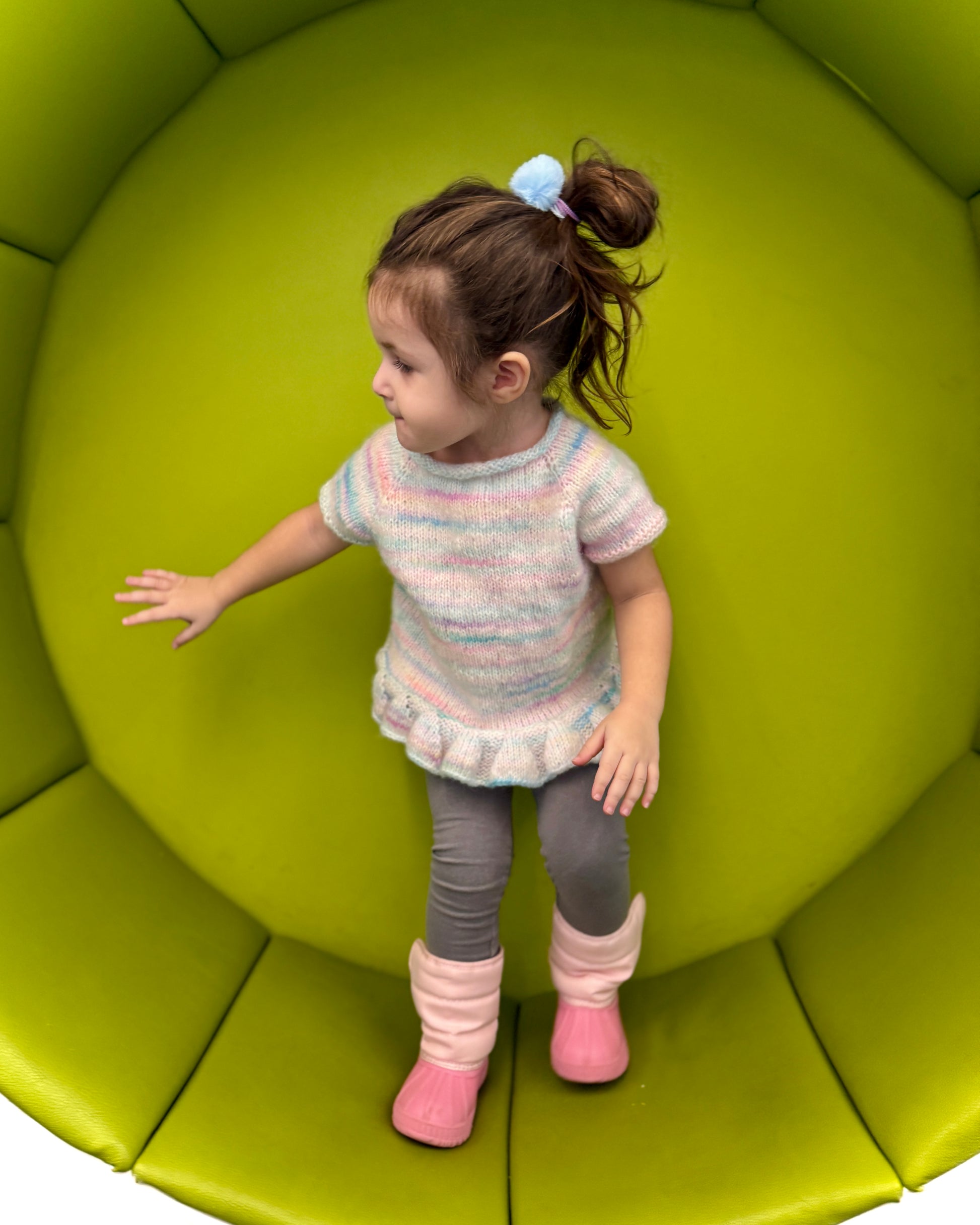 Child standing on a green cushioned surface