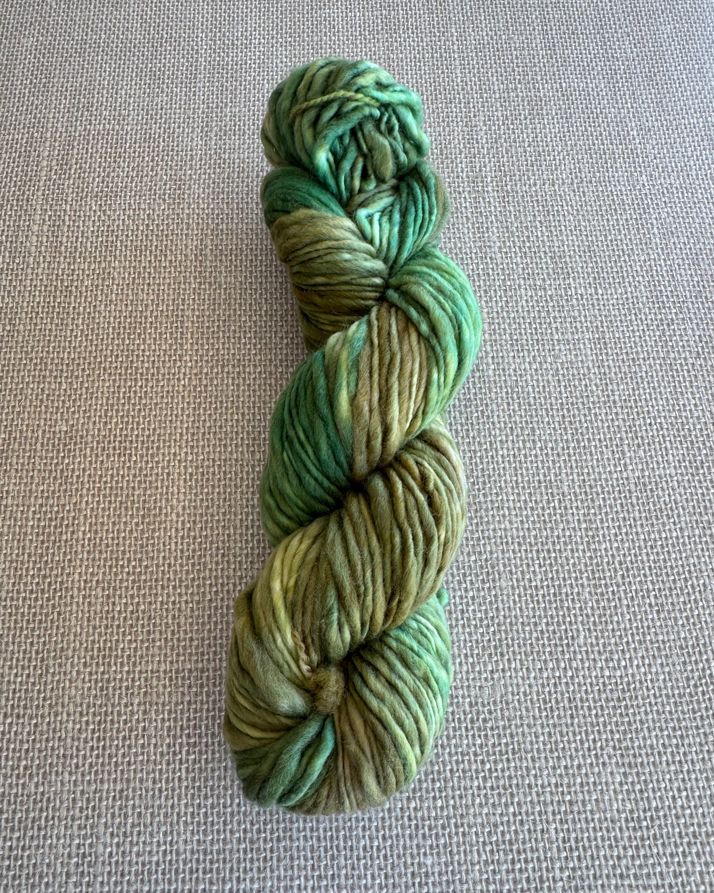 Green skein of yarn on a textured gray background