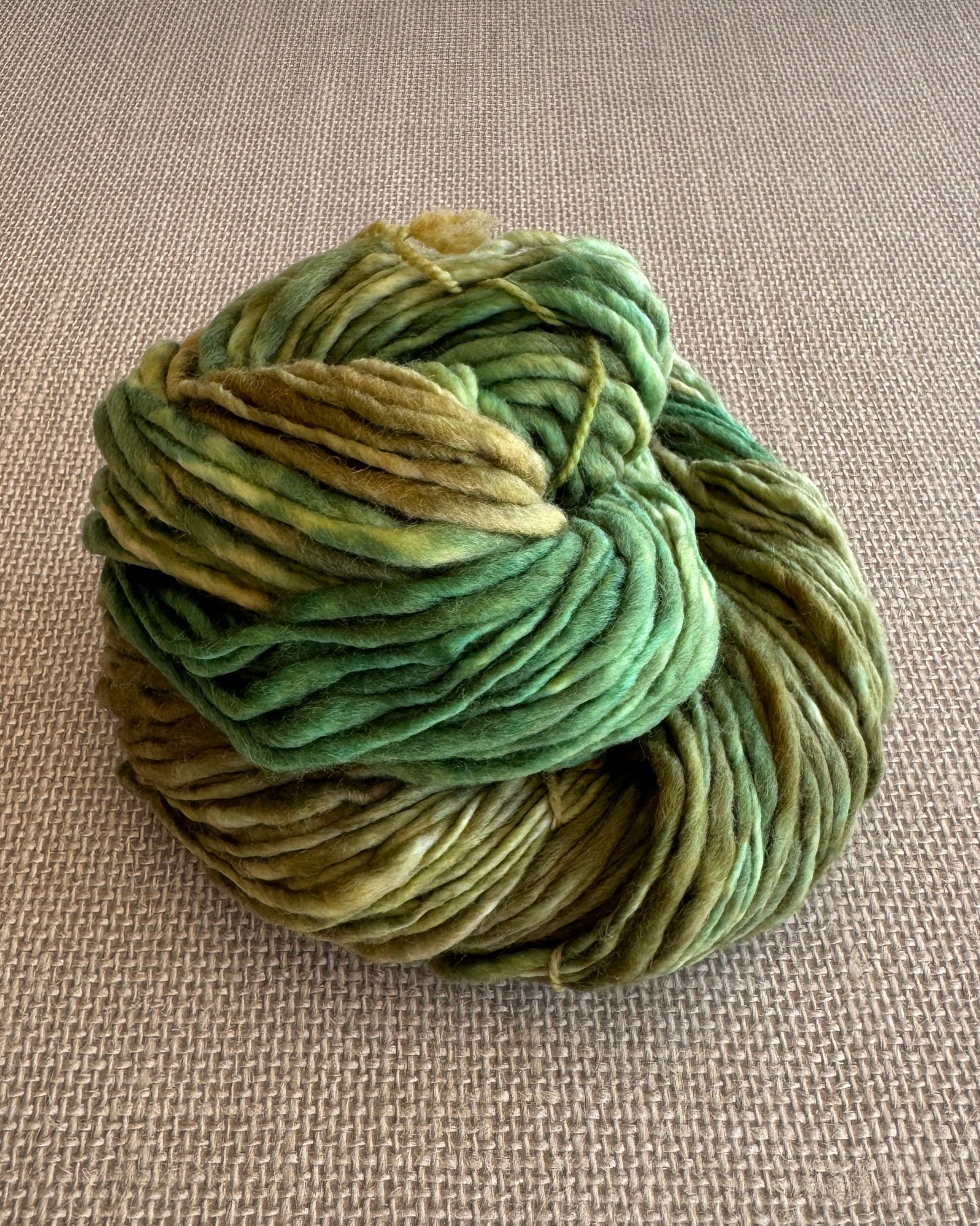 Green skein of yarn on a beige fabric background