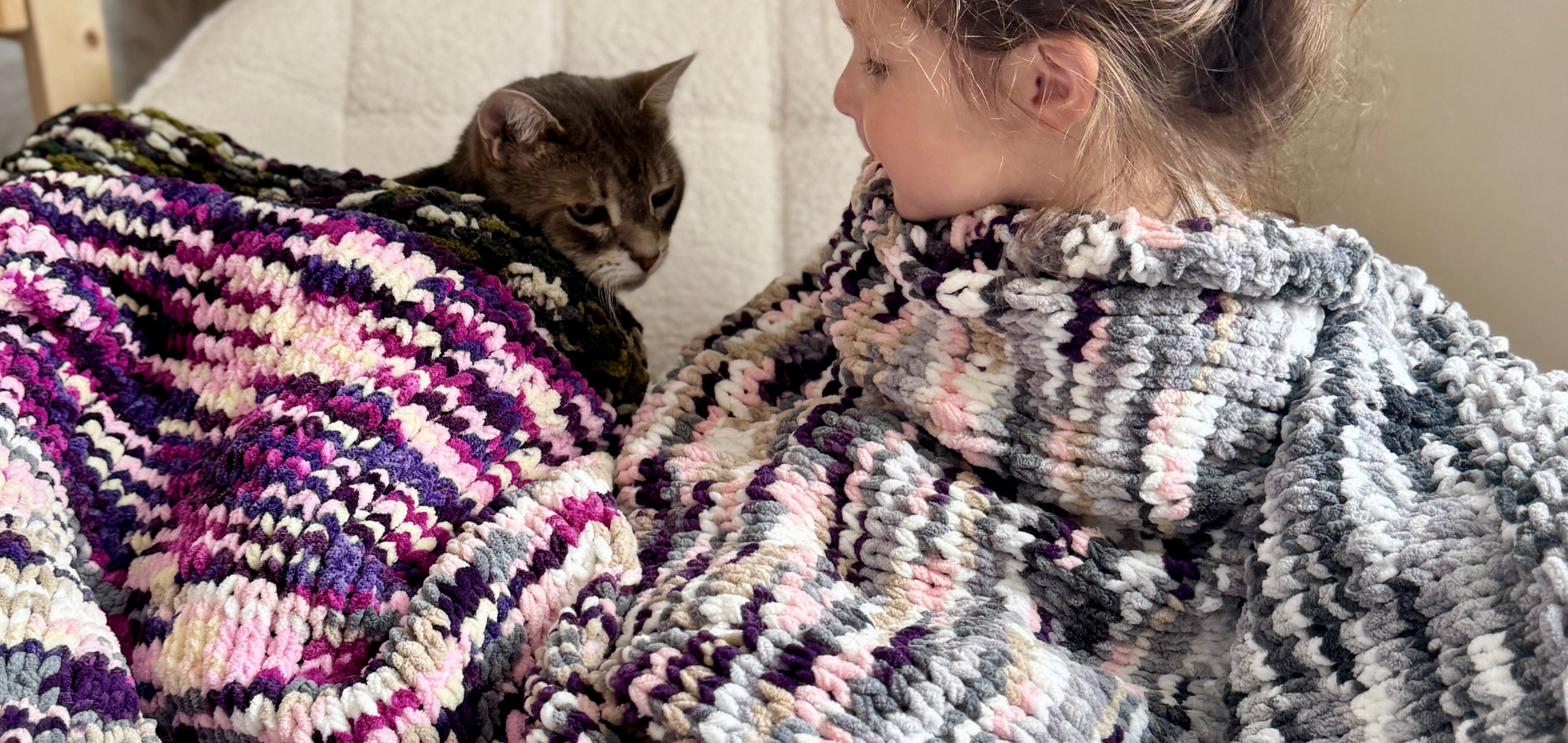 Baby and cat wrapped in knit blanket