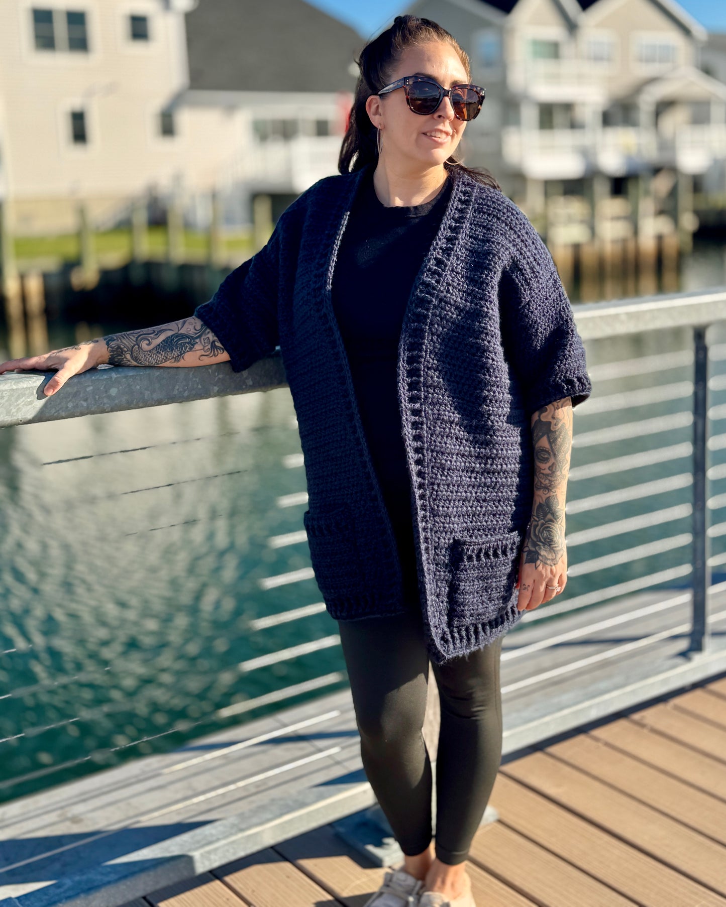 Handmade navy blue crochet cardigan with front pockets, styled by the water.